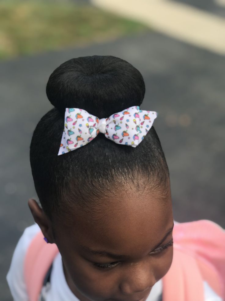 Child with a smooth top bun and colorful bow