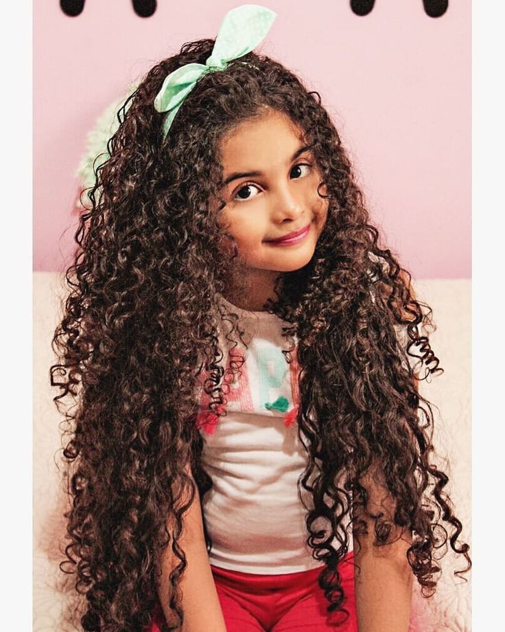 "Smiling girl with long voluminous curly hair and bow