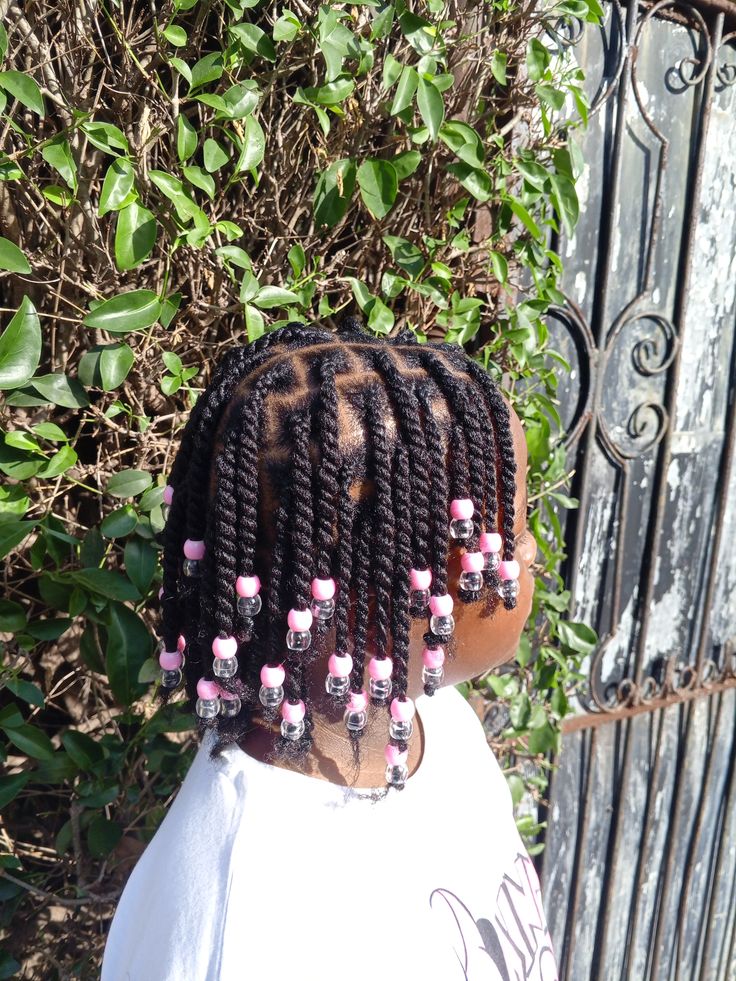 Young girl with small two-strand twists throughout, each ending in pink and clear beads