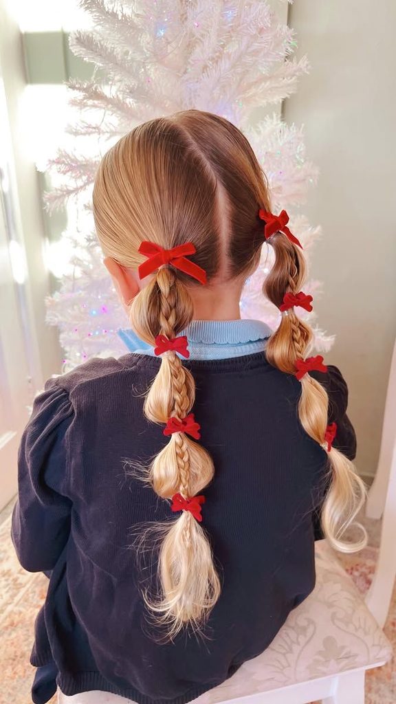 Girl with braided bubble pigtails decorated with small red velvet bows.