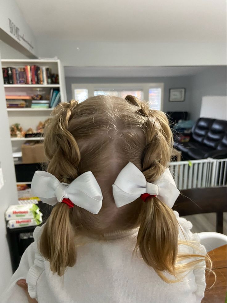 Toddler with twisted pigtails tied with white bows"