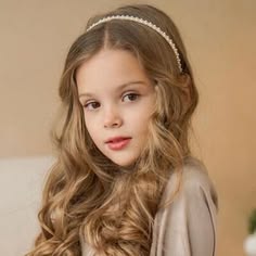 Girl with a pearl headband over wavy hair.