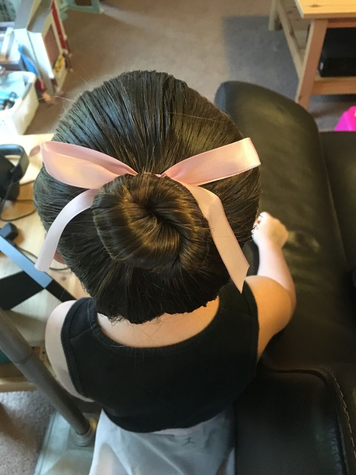 Overhead view of a girl's smooth ballet bun tied with a pink ribbon.