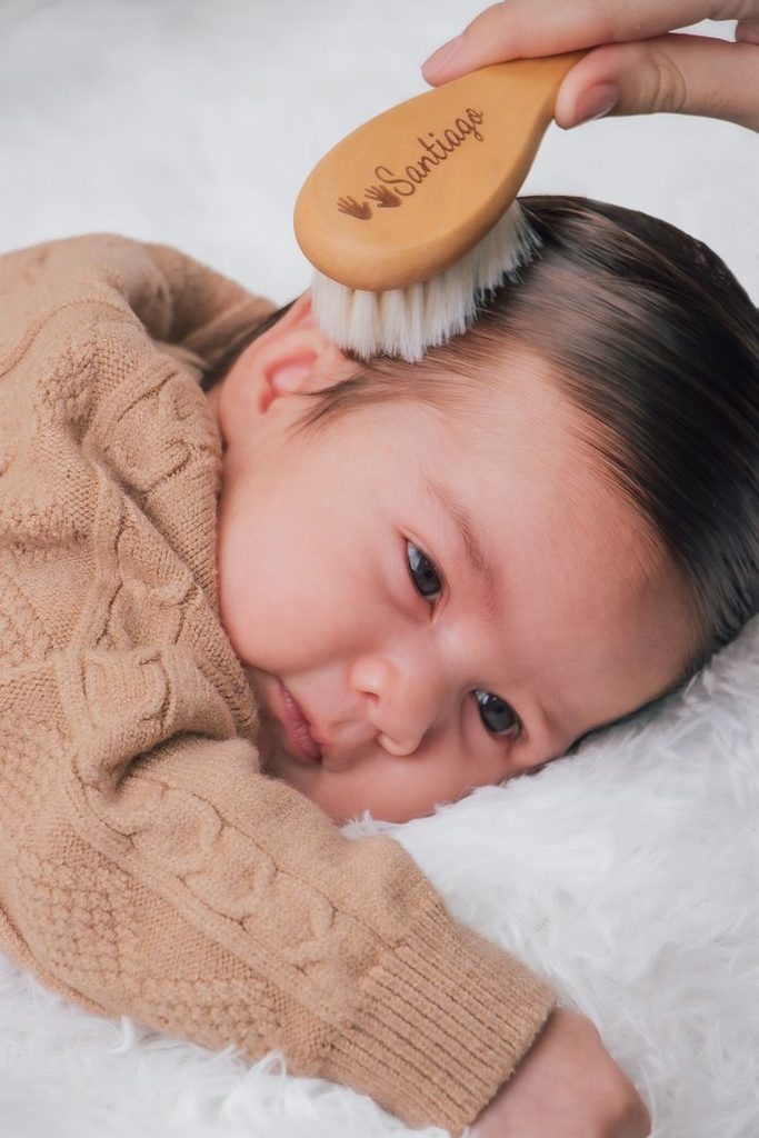 Soft brush gently brushing a newborn's hair