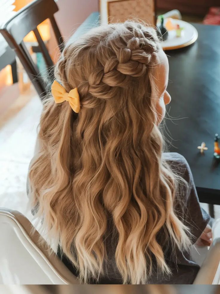 Child with a crown-style braid and wavy hair, decorated with a bow