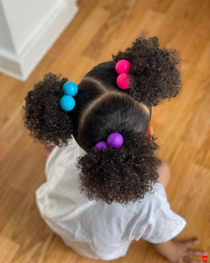 Child with three curly afro puffs and colorful bead ties