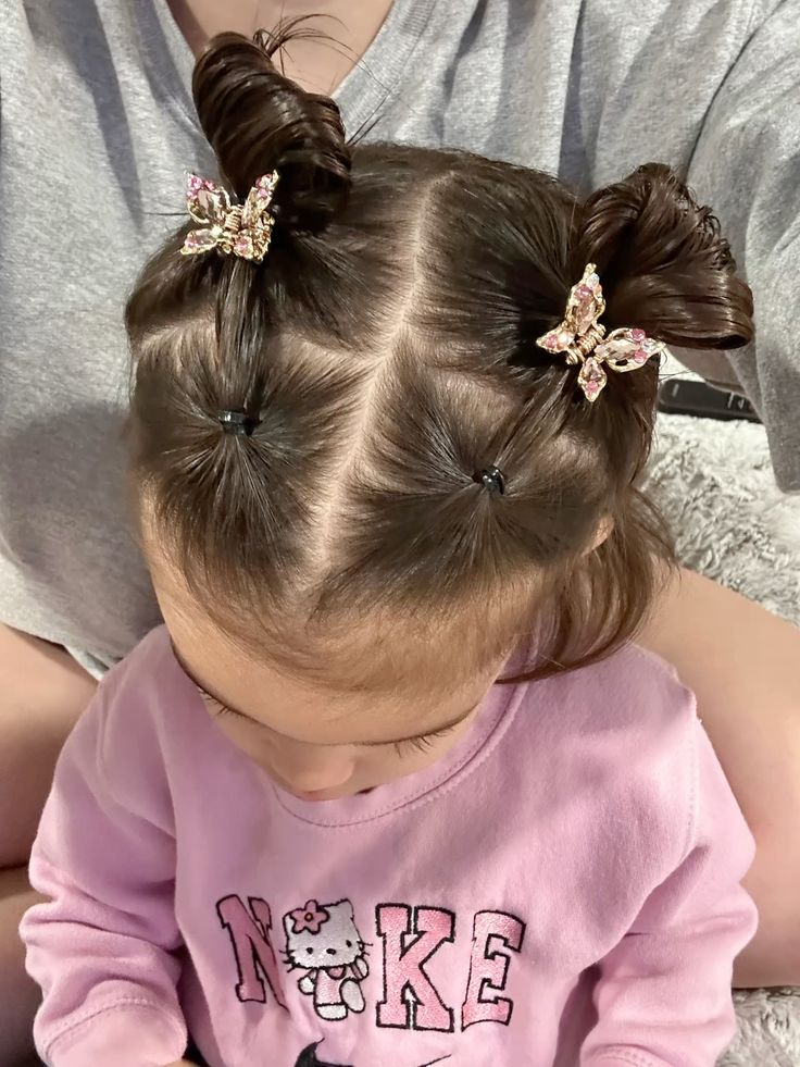 Toddler's hair styled into two buns with butterfly clips