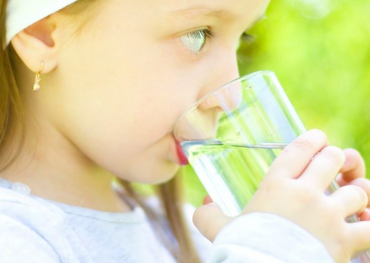 Young girl drinking a glass of water outdoors