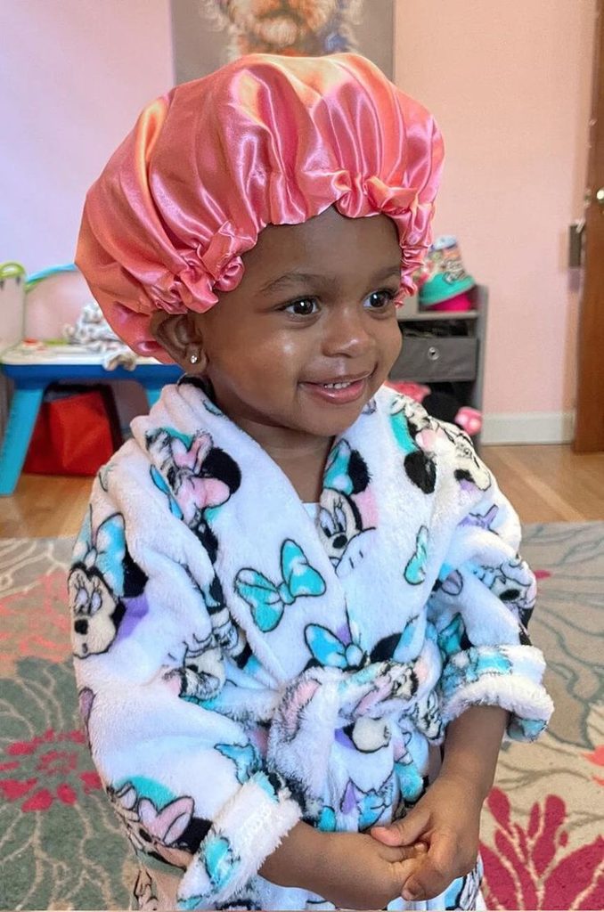 Toddler wearing a pink satin bonnet and robe