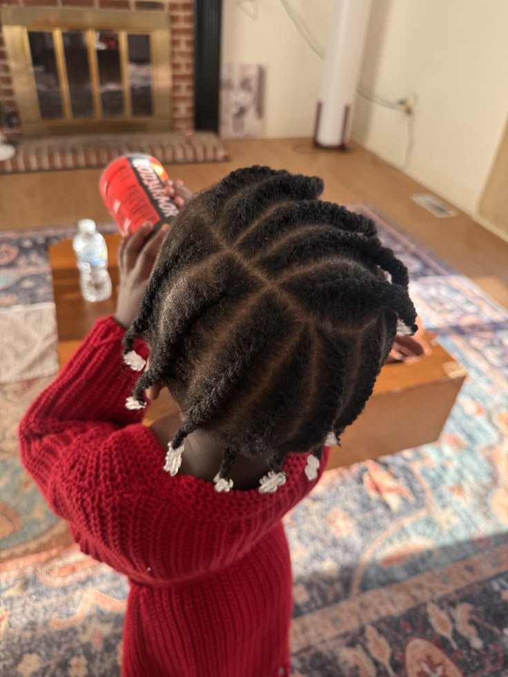 Toddler with hair styled in a radial pattern of flat twists with beads