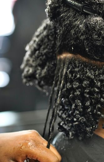 Close-up of a hand applying product to wet, curly hair."