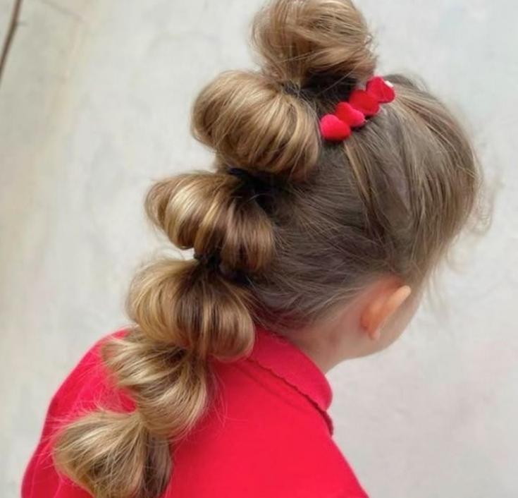 Girl with a high bubble ponytail styled in evenly spaced sections