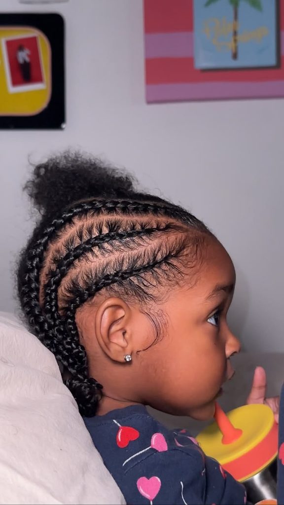 Toddler with cornrows and a curly puff, sipping from a cup