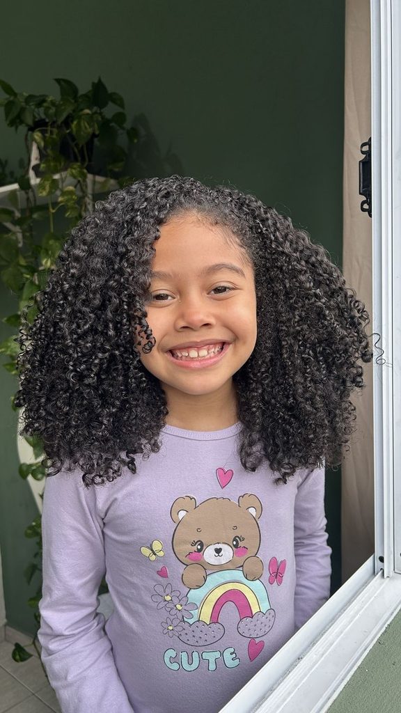 Smiling girl with long defined curly wash and go hairstyle