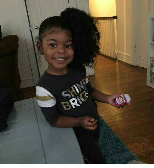 "Smiling little girl with a curly side ponytail hairstyle