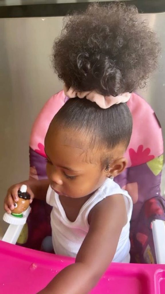 Toddler with hair gathered into a high curly puff