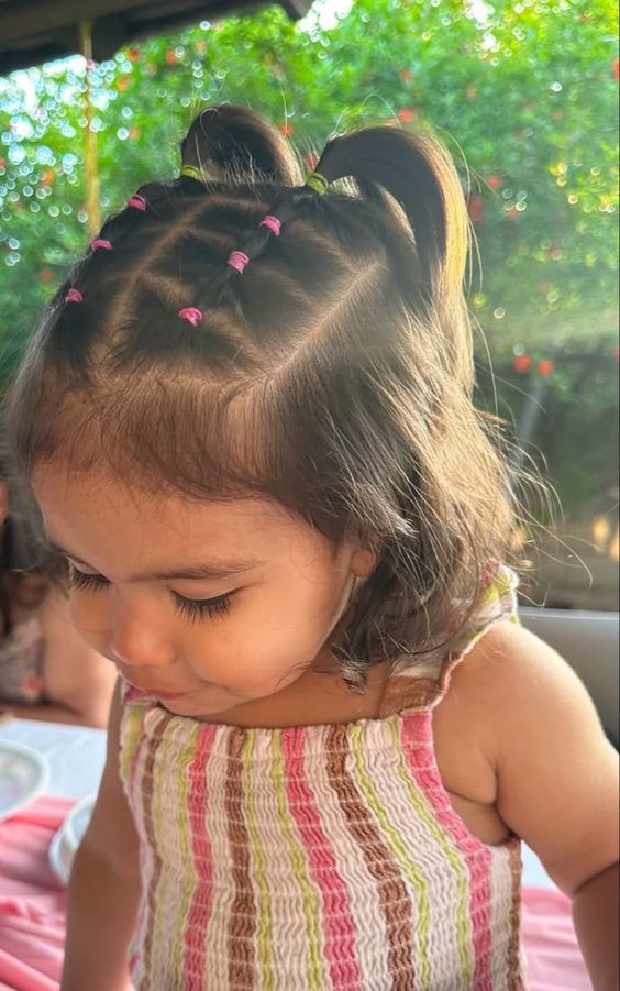 Toddler with hair sectioned into small rows leading to two top ponys