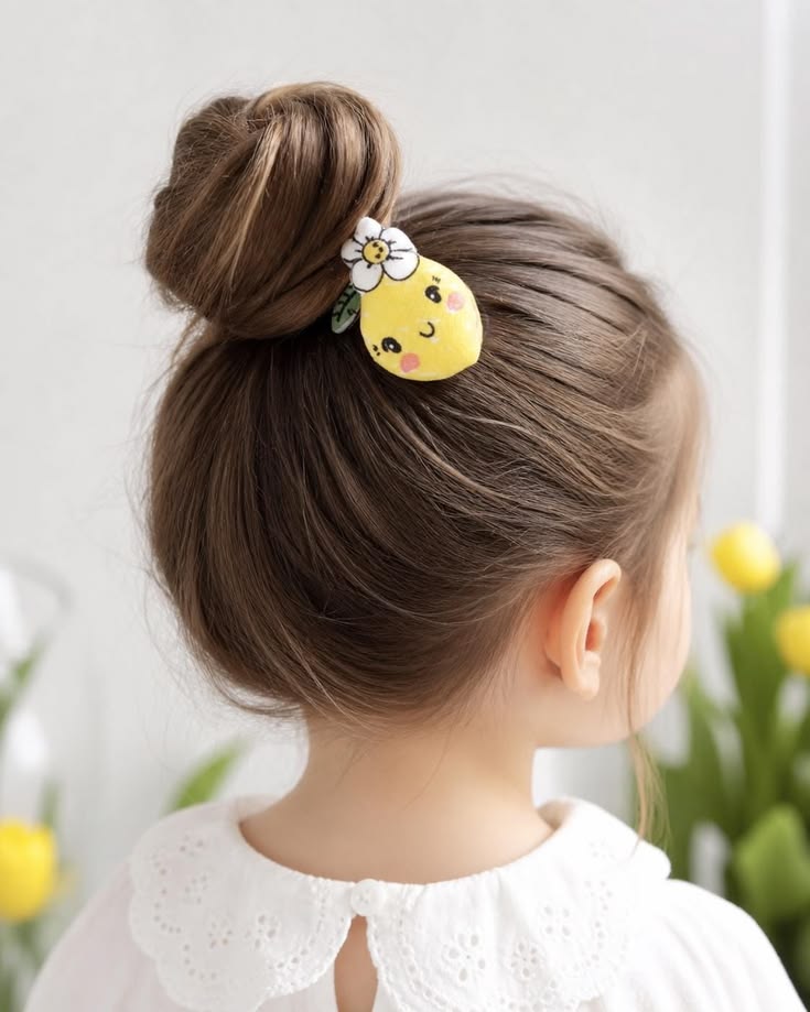 Toddler with hair in a small top knot with a lemon-shaped clip