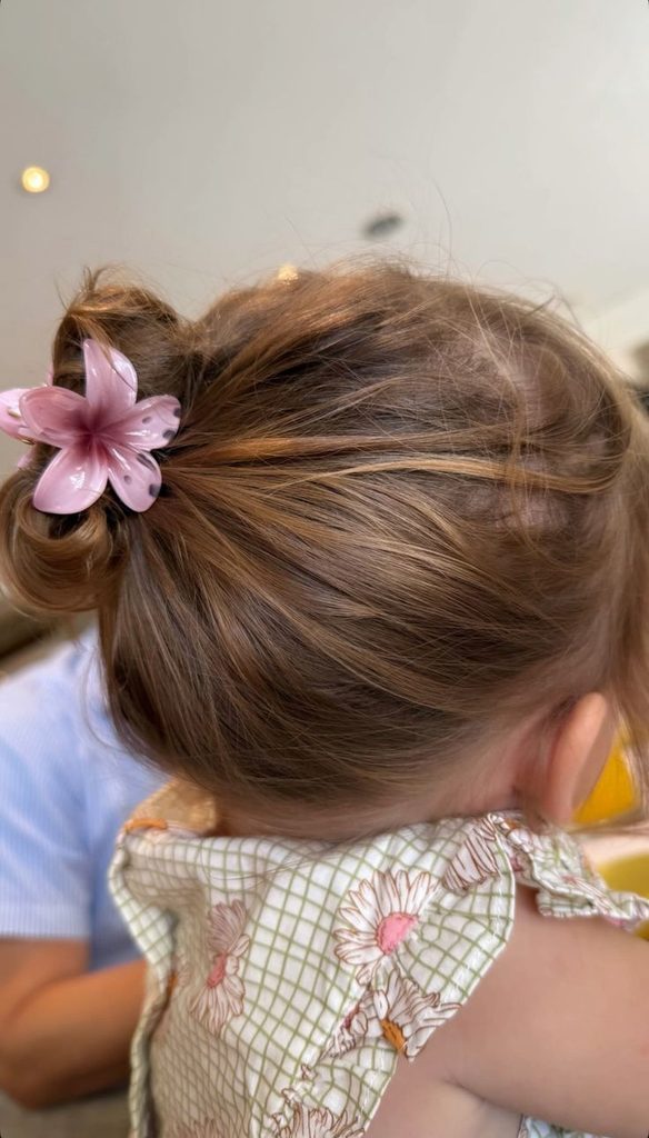 Toddler with a small low bun and a pink flower clip