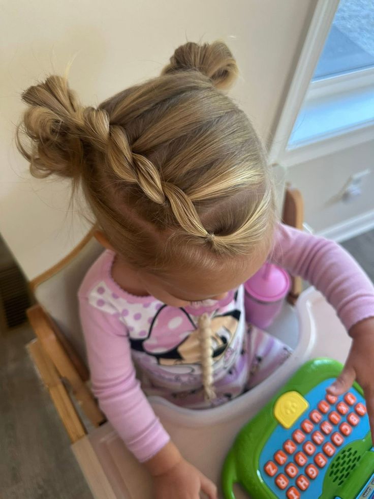 Toddler with two small top buns connected by a one-sided twist"