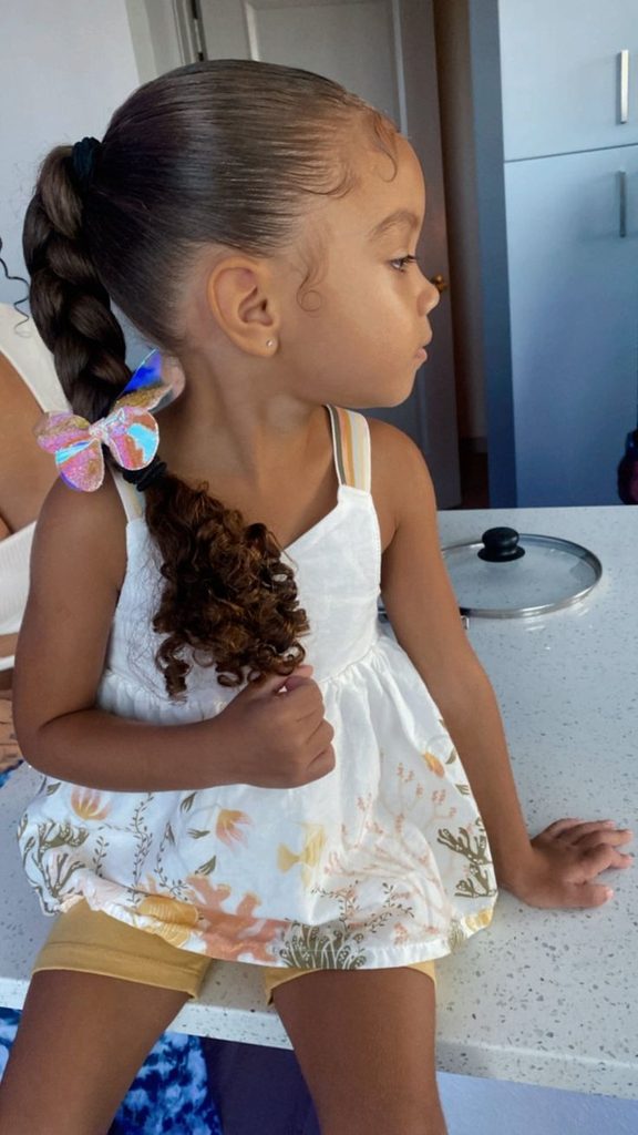 Child with a braided ponytail and curly ends, butterfly clip