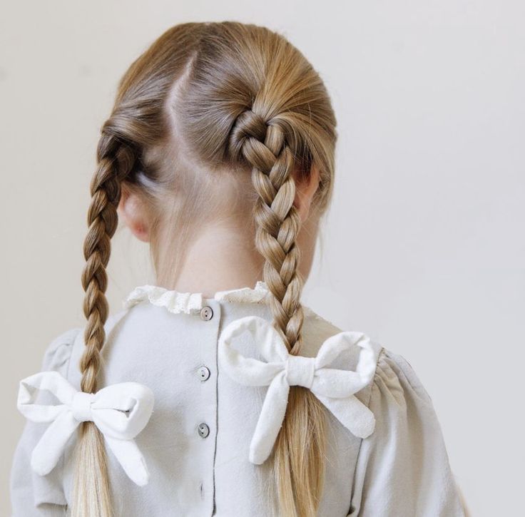 Child with braided pigtails and white bows