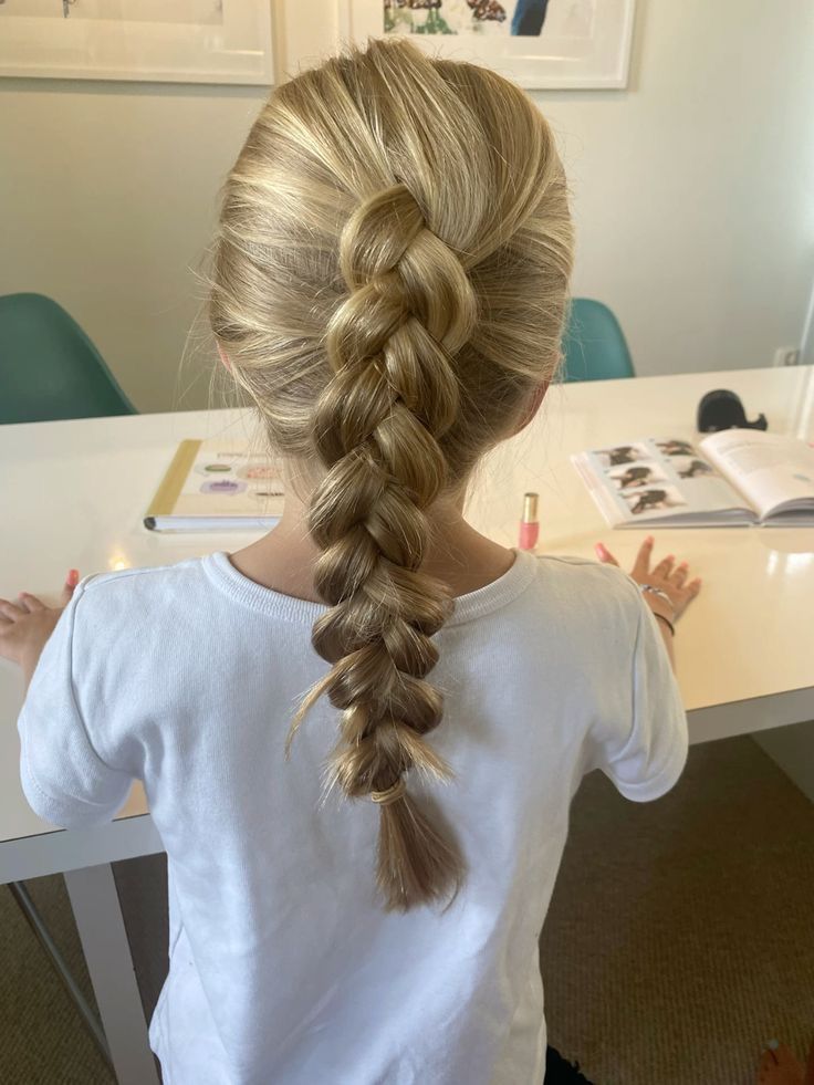 Child with a braided ponytail at a desk"
