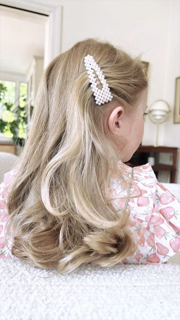 Girl with long blonde curls pulled back on one side with a pearl barrette, soft waves flowing down her back
