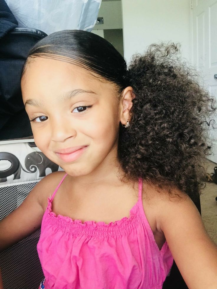 Young girl with a curly side ponytail, smiling for the camera