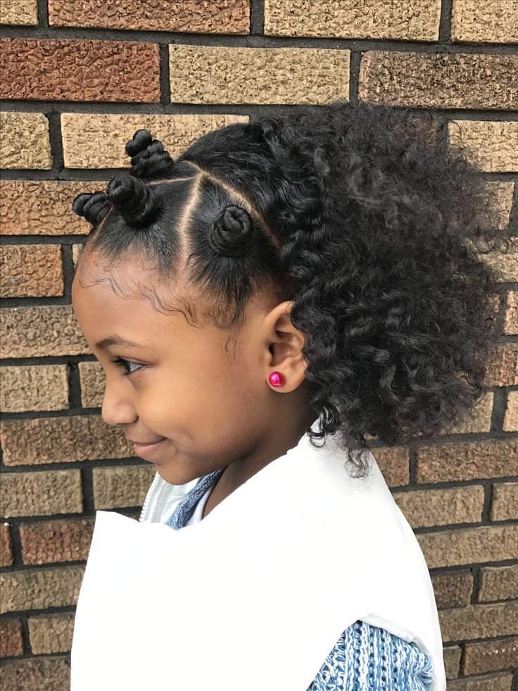 Young girl with mini bantu knots along the hairline and a curly puff, shown in profile