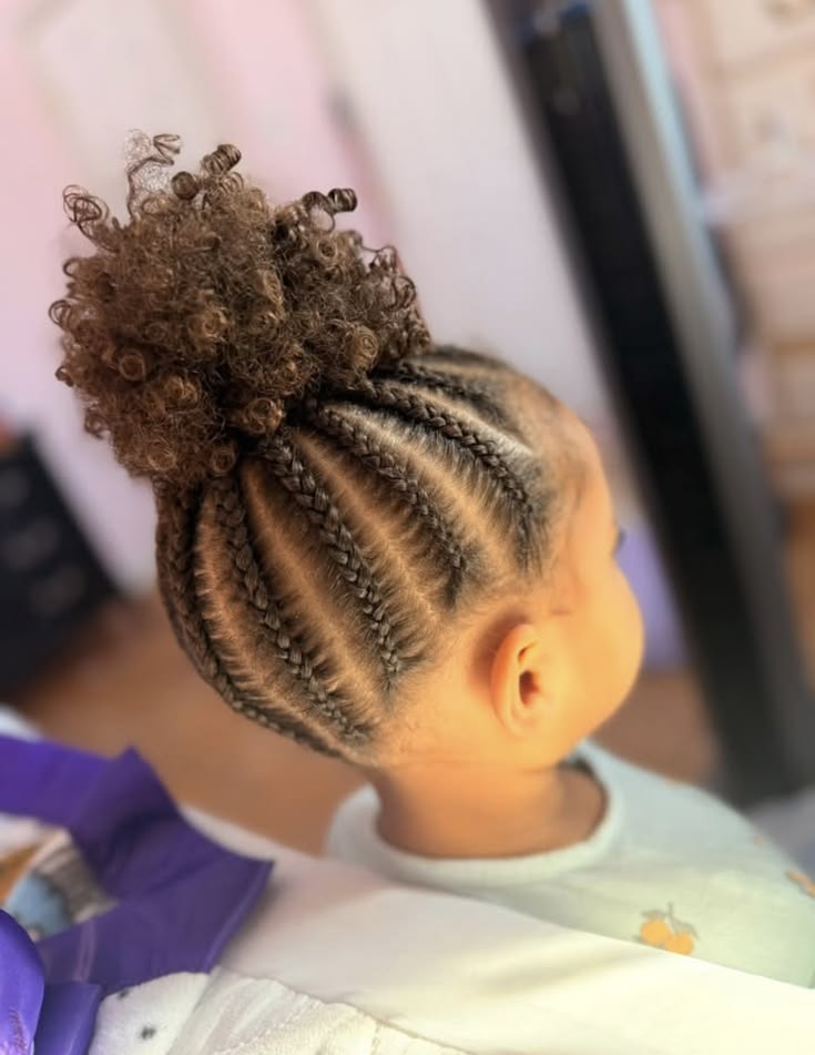 Young girl with curved cornrows leading into a high curly puff, shown in profile