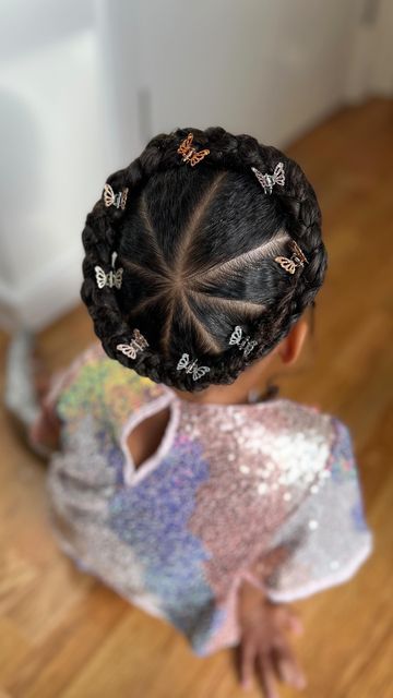 Young girl with a braided crown in a sunburst pattern, decorated with small butterfly clips, shown from above