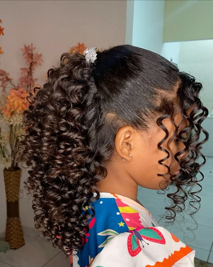 Girl with a curly half-up half-down hairstyle secured with a clip.