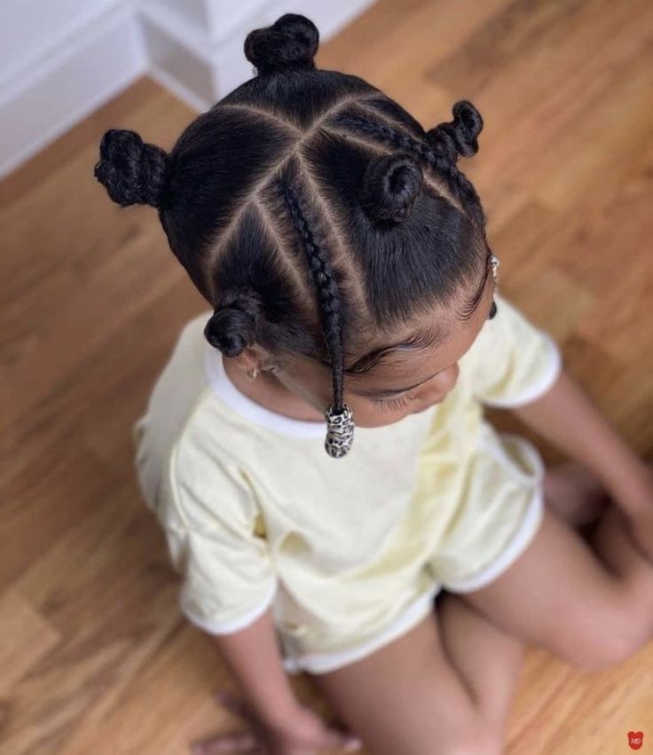 Overhead view of a girl with Bantu knots and one braided accent section, finished with a beaded end.