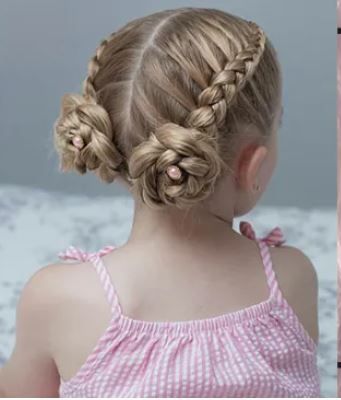 Girl with braided pigtails wrapped into two buns and secured with pink pins.