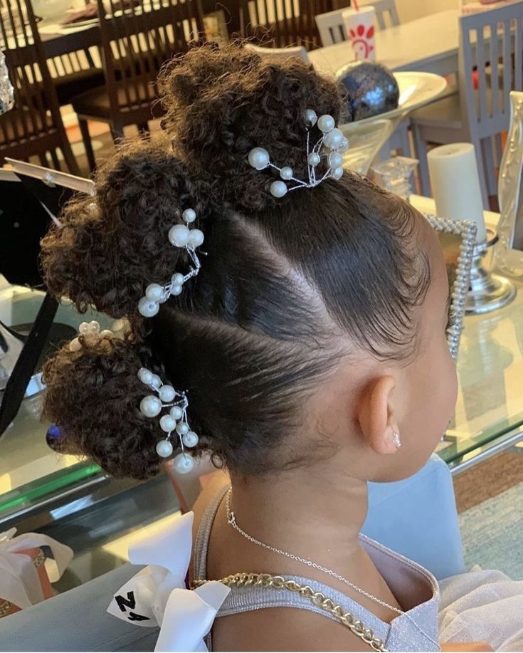 Girl with three stacked curly buns decorated with pearl accents."