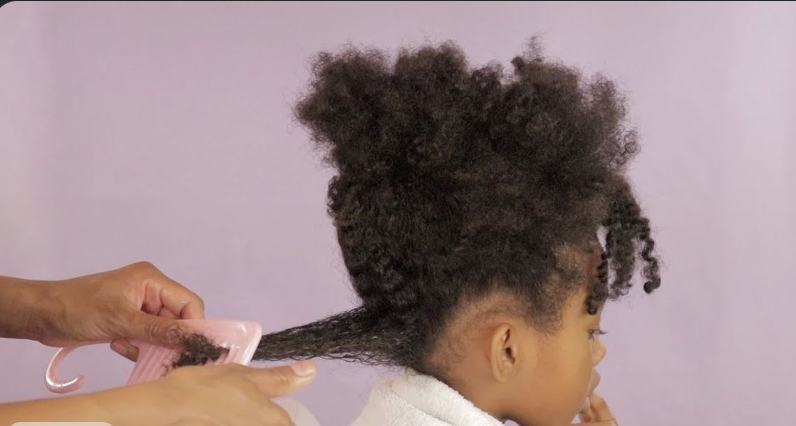 Adult combing a child's curly hair starting from the ends
