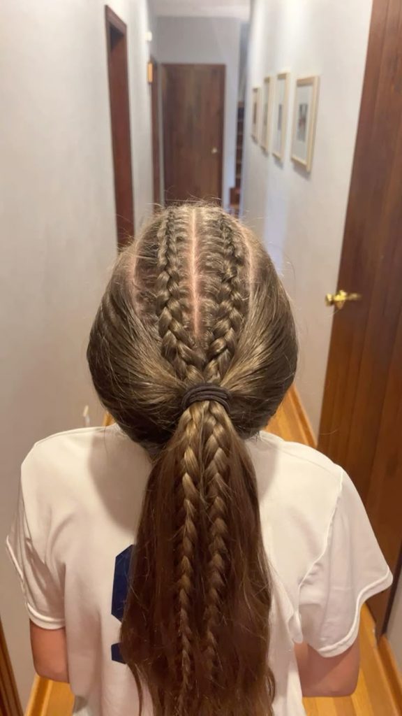 Girl with two mini Dutch braids leading into a ponytail