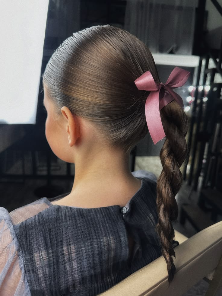 Girl with a sleek twisted ponytail tied with a mauve ribbon