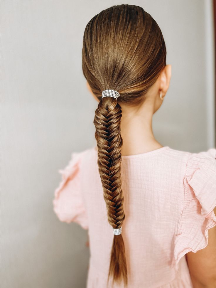 Girl with a sleek ponytail braided in a fishtail and tied with sparkly elastics